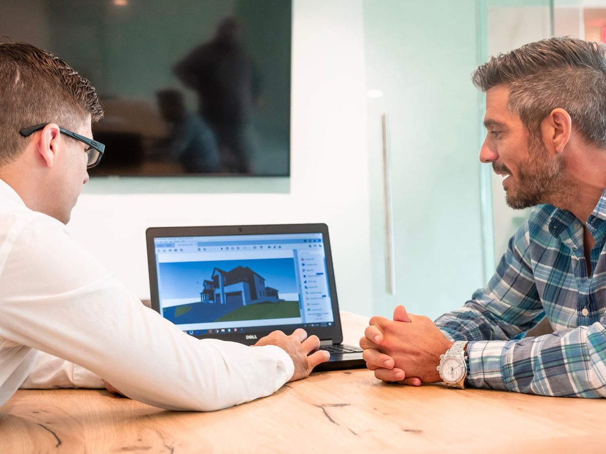 Design engineer walking a client through a 3D CAD model on a laptop