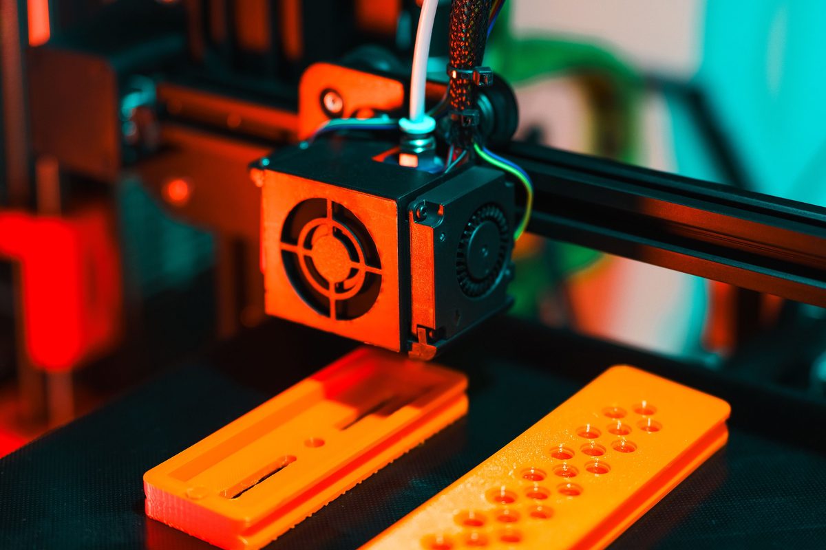FDM 3D printer building orange rapid prototype parts on the print bed