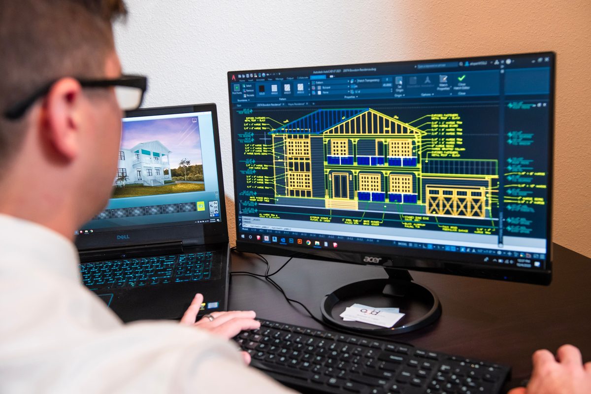 Designer working on a 2D AutoCAD drawing alongside its 3D model on a second screen