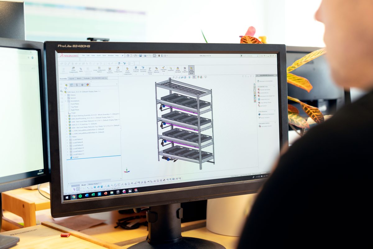 CAD engineer building a 3D parametric assembly in SolidWorks on a desktop workstation